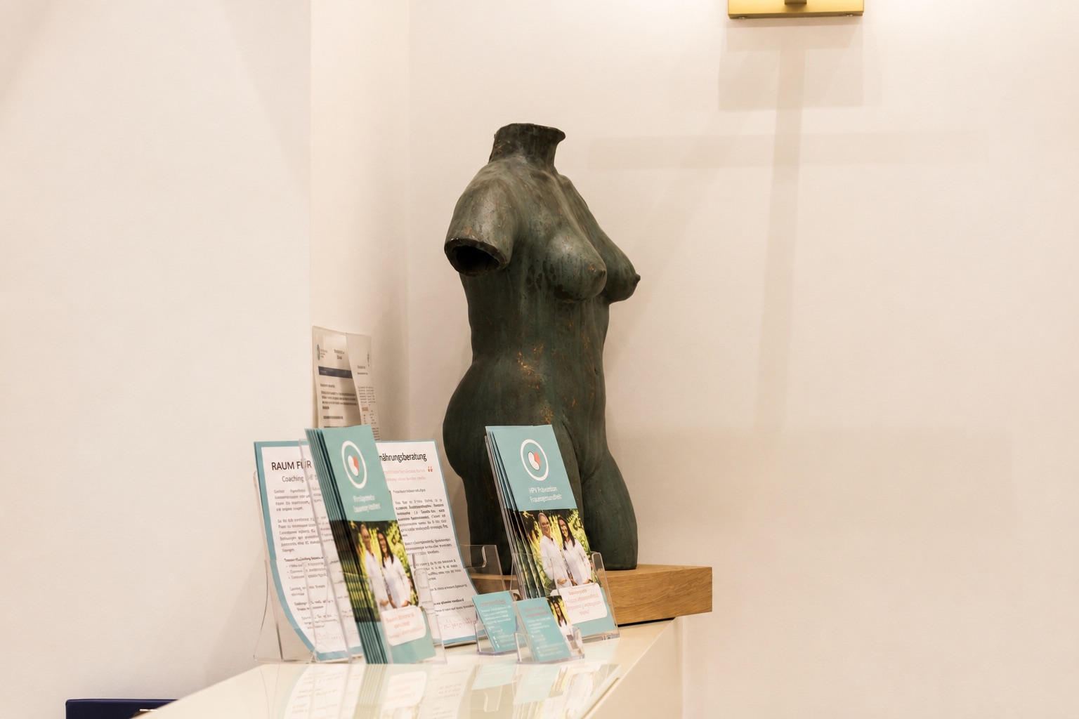 Bronzeskulptur und Informationsbroschüren im Empfangsbereich der Praxis